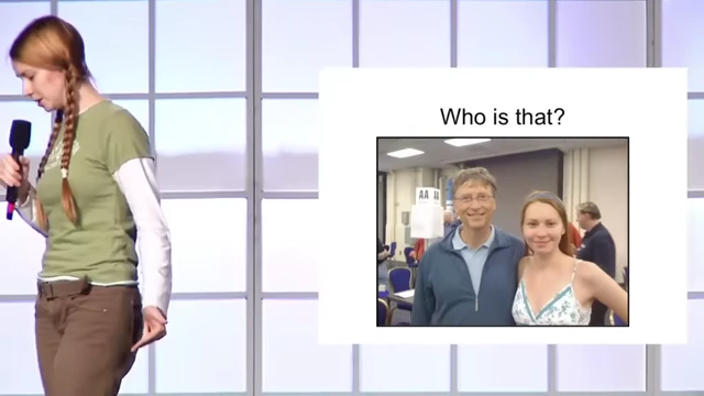 Mila Antonova on stage giving a presentation with a photo of her and Bill Gates on the screen behind her.
