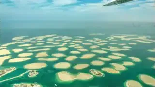 An aerial view of the Dubai World Islands, showing numerous small, irregularly shaped man-made islands in turquoise water.