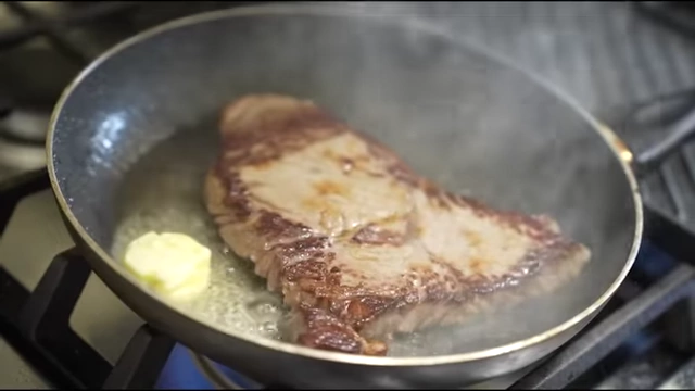 Ribeye steak cooked with a significant amount of butter.