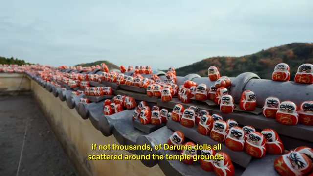 Hundreds of small Daruma dolls, symbolizing perseverance and good luck, arranged on the ledges and grounds of Katsuo-ji Temple.