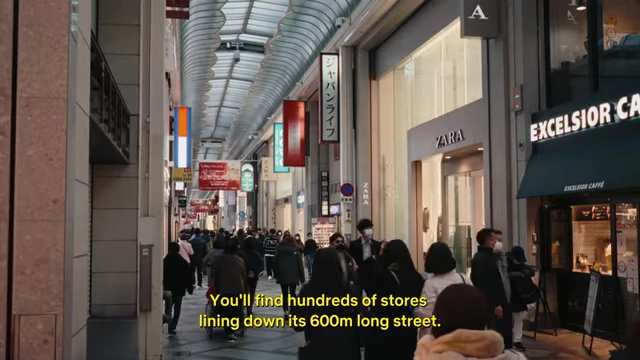 A bustling view of the Shinsaibashi shopping street, an indoor arcade lined with various stores and shoppers.