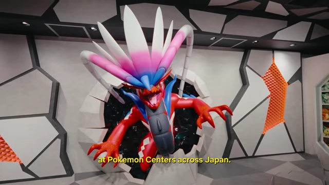 A large, dynamic display of a red and blue Pokemon character bursting through a wall at the Pokemon Center in Umeda.