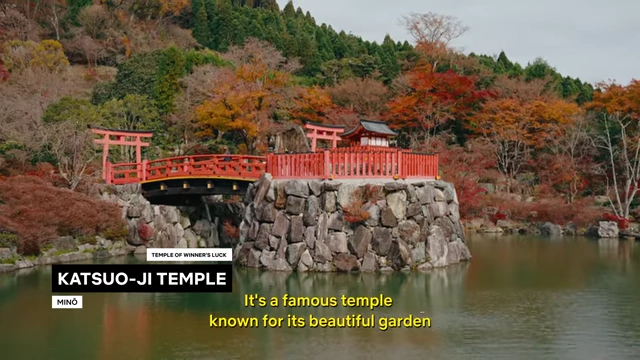 The serene Katsuo-ji Temple grounds feature a traditional red bridge spanning a misty pond, surrounded by autumn foliage and a temple gate.