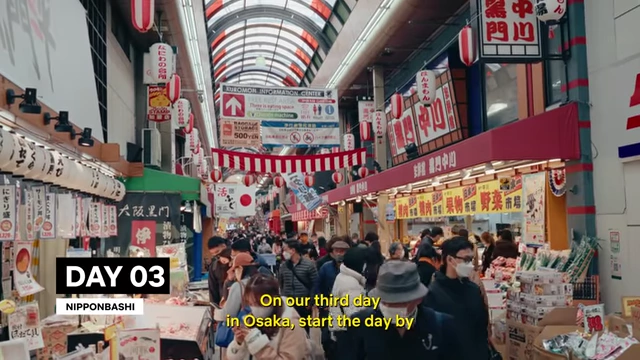 The bustling Kuromon Market street, with a high arching ceiling and numerous food stalls and shoppers.