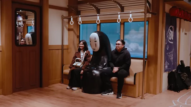 Two people posing for a photo with a large No-Face character from Studio Ghibli's Spirited Away, inside the Donguri Store in Namba.