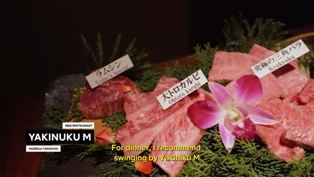 A beautifully presented platter of various cuts of high-quality raw meat for yakiniku, garnished with greenery and a flower, at Yakiniku M.