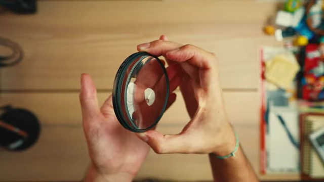 A macro close-up filter being held, showing its bulbous element