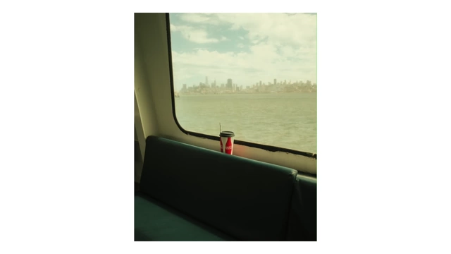 A window view from a ferry with a soda can, showing the distant New York City skyline