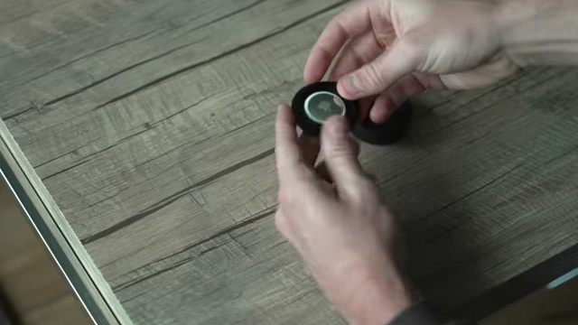 A close-up of an Apple AirTag, a small tracking device, held in a person's hand