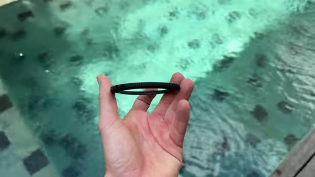 A small black step-up ring held over water, demonstrating its size