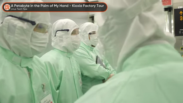 Cleanroom engineers in protective suits observing the delicate semiconductor manufacturing process.