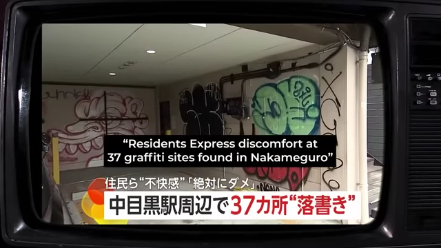 A television screen displaying a news report with Japanese text at the top and bottom, featuring an image of graffiti on a wall and a caption reading "Residents Express discomfort at 37 graffiti sites found in Nakameguro."