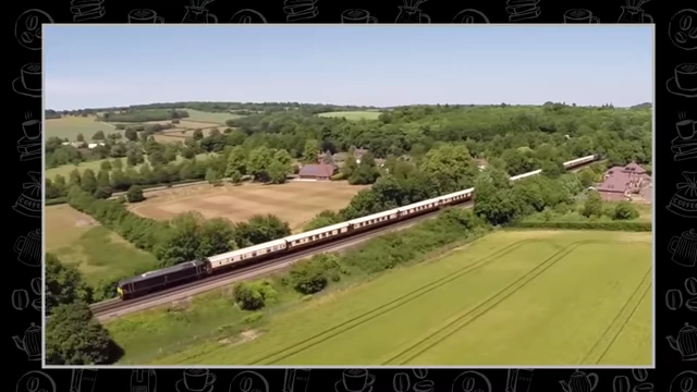A scenic view of a luxurious train traveling through a green countryside.