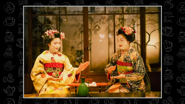 Two Geisha women in traditional kimonos sit across from each other, engaged in a conversation or performance.