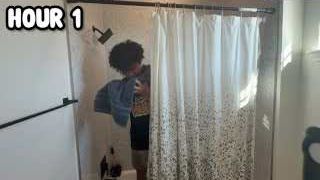 The presenter in a shower, behind a shower curtain, with the text "HOUR 1" overlaid.