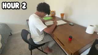 The presenter sitting at a desk, writing notes in a notebook next to an open book, with the text "HOUR 2" overlaid.