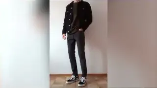 A person wearing slim, straight-leg dark jeans and a dark shirt with a denim jacket.