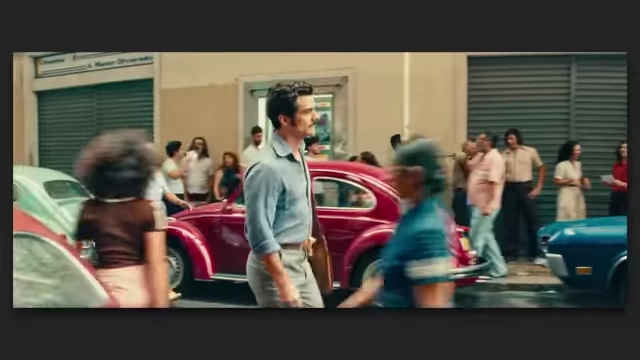 A man walks through a vibrant, bustling street scene in Brazil from "The Secret Agent."