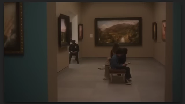 Two figures move through a museum hall with paintings on the walls in "The Mastermind."