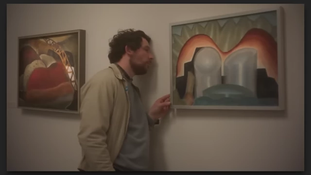 A man examining a painting intently in "The Mastermind," reflecting on the protagonist's delusions and "genius" self-image.