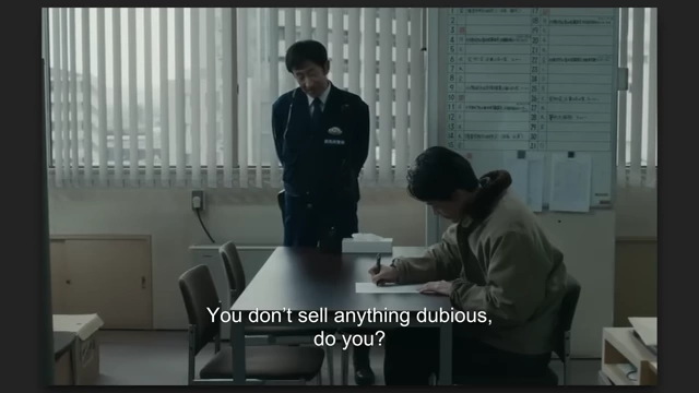 A man sitting at a desk being questioned by a police officer, illustrating the consequences of online actions in "Cloud."