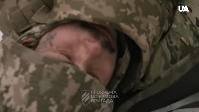 A soldier resting or sleeping, wrapped in camouflage clothing
