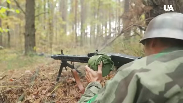 Soldiers in historical uniforms in a forest setting, depicting WWII combat