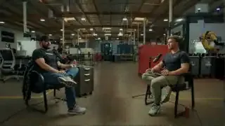 Jim Belosic (left) and the interviewer (right) discuss business strategies in a factory setting.