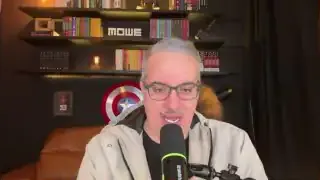 The speaker with shelves of books and a Captain America shield in the background.