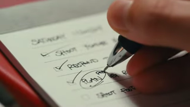 A hand writing on a small notepad with a checklist, circling "PLAN".