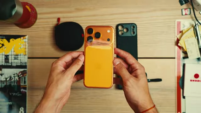 Two iPhone cases, one with a unique camera bump, being held up to discuss gear choices.