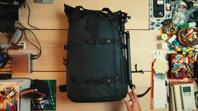 A camera backpack and accessories neatly arranged on a table, illustrating organized gear.
