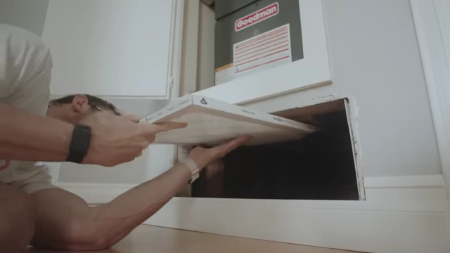A person installing a new MERV filter into an HVAC system.