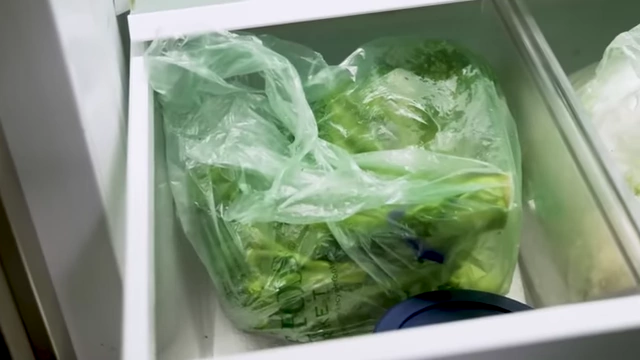 A plastic bag containing vegetables is seen inside a refrigerator drawer, illustrating hidden plastic.