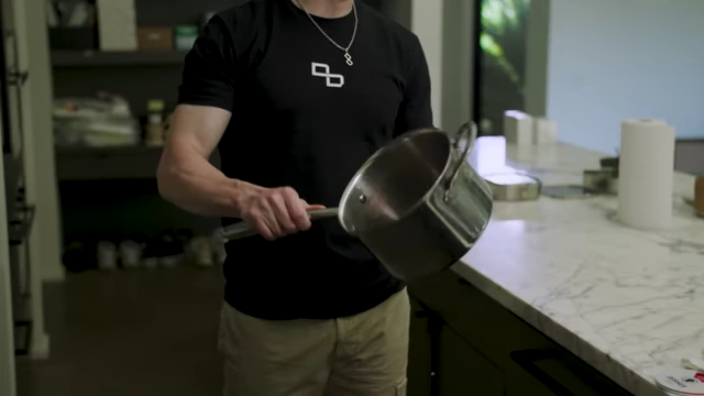 Bryan Johnson holds up a stainless steel pot, recommending it as a safer alternative to non-stick pans.