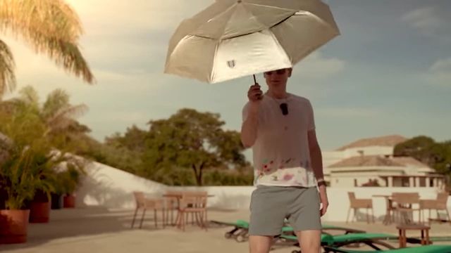 Bryan Johnson demonstrates sun protection by using an umbrella and wearing a hat.