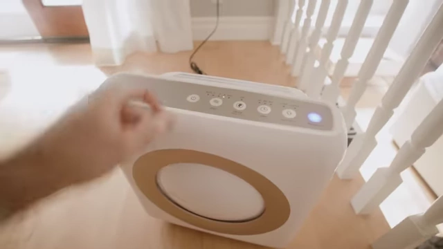 A hand turns on a portable HEPA air purifier.