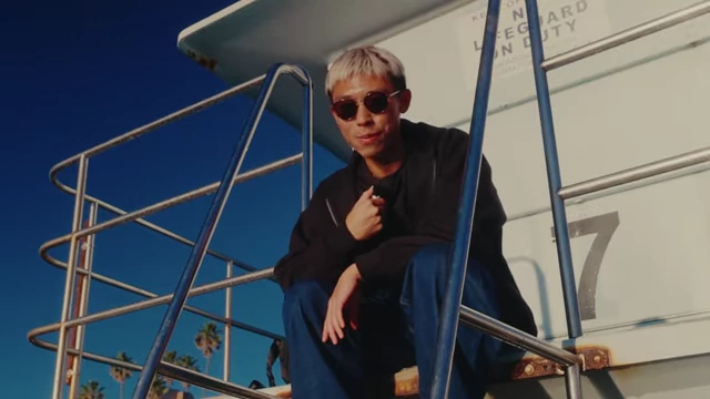 Benny Dong, the speaker, sitting on a lifeguard stand in Carlsbad with sunglasses