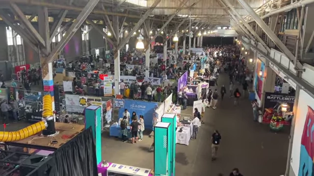 Overall view of the bustling Open Sauce expo hall, with various exhibits and attendees.