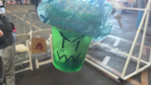 A green plastic cup with a blue plastic bag covering it, part of the egg drop contraption.