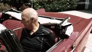 A grandfather happily sits in the driver's seat of his new classic car.