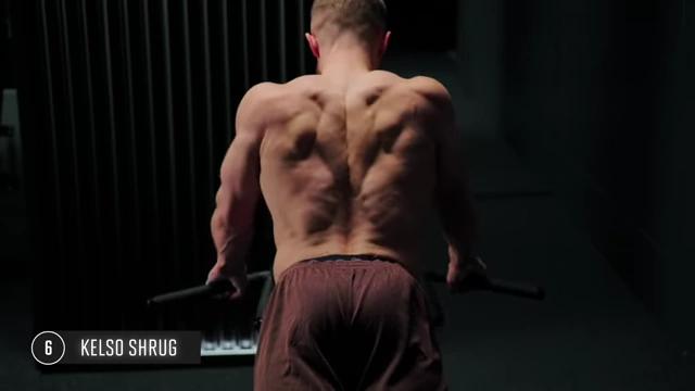 Man performing Kelso shrugs, showcasing the shoulder blade retraction and mid-back squeeze from a rear view