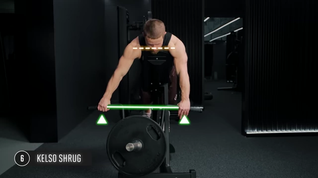 Man setting up for Kelso shrugs on a T-bar row machine with a wide grip and chest supported