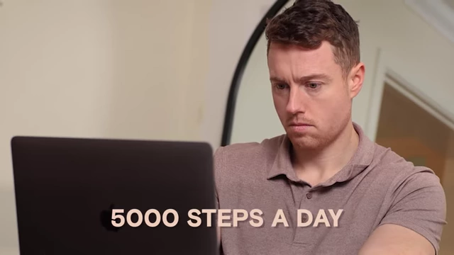 The speaker working on a laptop, with text showing typical daily steps [<a href="https://youtube.com/watch?v=qtP8qpMkweE&t=5000">5000</a>] contrasting with the increased requirement.