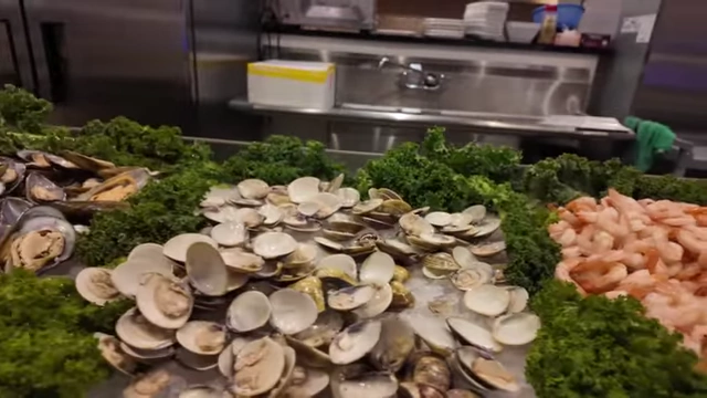 A selection of cold seafood like clams, mussels, and shrimp cocktail on ice.