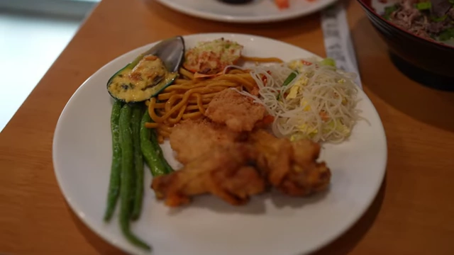 A plate filled with hot items like fried chicken, coconut shrimp, and noodles.