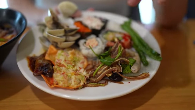 The second round plate, featuring steamed clams, eggplant, cold appetizers, and more sushi.