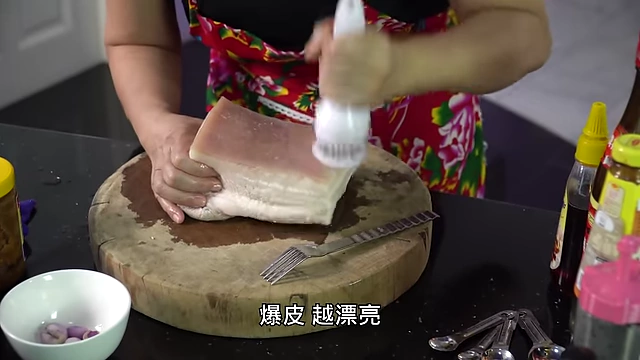 Puncturing pork belly skin with a meat tenderizer for crispiness.