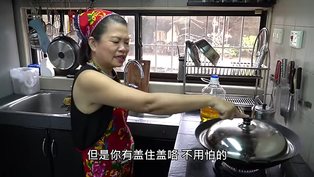 Covering the wok to prevent oil splattering during frying.
