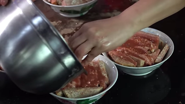 Pouring remaining sauce over the assembled pork and taro.